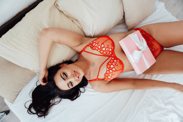 gyönyörű barna nő piros vászon az ágyon a hálószobában - Fotó, kép
