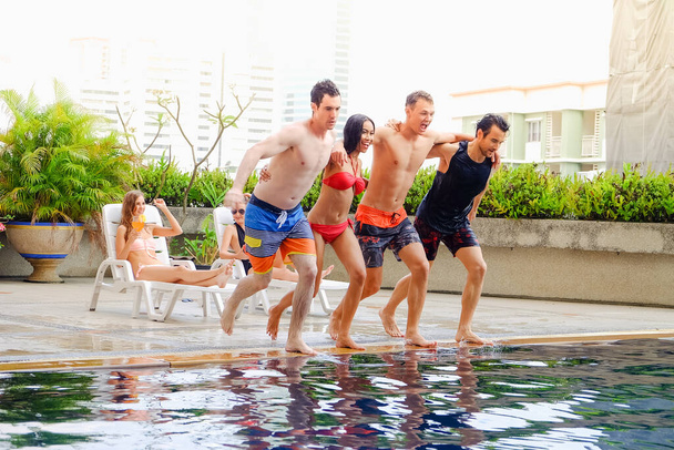 Портретная сексуальная вечеринка у бассейна в бикини наслаждается встречей с друзьями в бассейне, счастливой жизнью в летний сезон - Фото, изображение