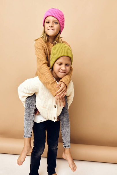 κοριτσάκι και αγόρι χαμογελώντας και ποζάροντας σε casual ρούχα μπεζ φόντο - Φωτογραφία, εικόνα