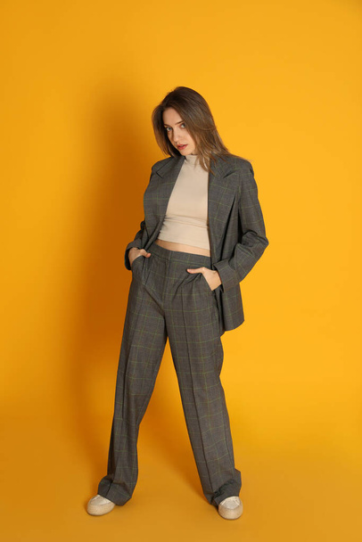 Full length portrait of beautiful young woman in fashionable suit on yellow background. Business attire - Fotografie, Obrázek
