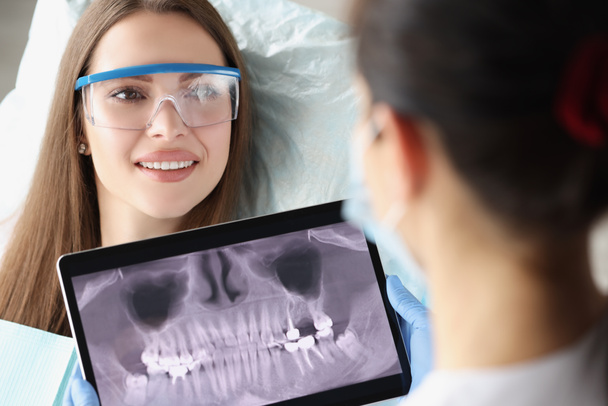 Pacjent po konsultacji stomatologicznej w klinice, lekarz bada zęby rentgenowskie na tablecie cyfrowym - Zdjęcie, obraz