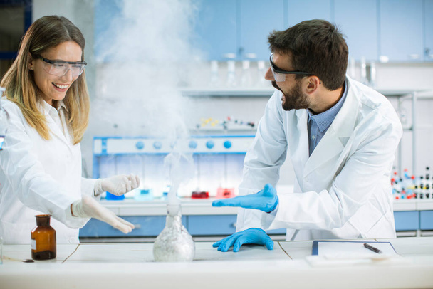 Jovens pesquisadores fazendo experimentos com fumaça em uma mesa de um laboratório químico - Foto, Imagem