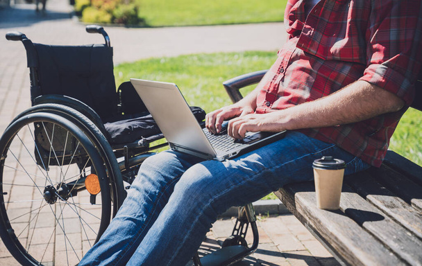 Freelancer with a physical disability in a wheelchair working at the park - Foto, immagini