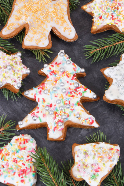 Fresh baked homemade gingerbread with colorful decorations and green spruce branches. Christmas time - Фото, зображення