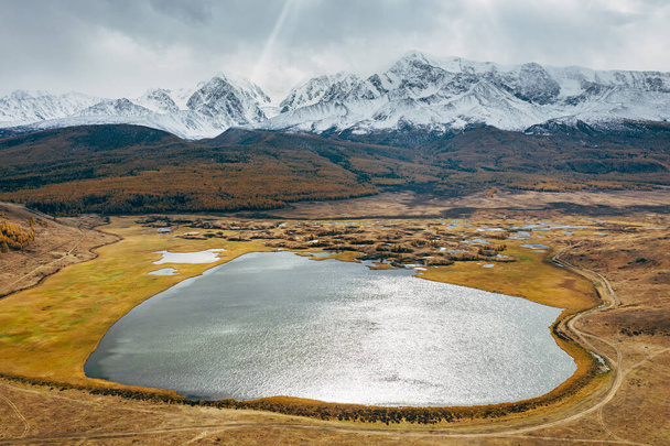 Lake in autumn against the background of snow-capped mountains in Altai - 写真・画像