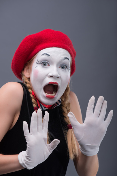 Waist-up portrait of young mime girl showing something - 写真・画像
