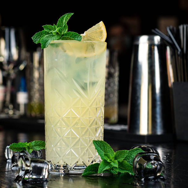 Refreshing non-alcoholic cocktail lemonade with lemon slice and mint. Fresh cool detox water drink with lemon. Lemonade with mint. proper nutrition and healthy eating. Fitness diet. - Фото, изображение