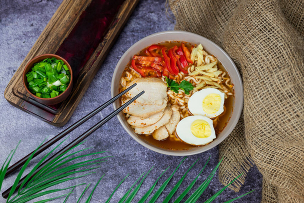 ζεστό νόστιμο ιαπωνικό noodle σούπα ράμεν με λαχανικά κοτόπουλο, πράσινα κρεμμύδια και αυγό με chopsticks - Φωτογραφία, εικόνα
