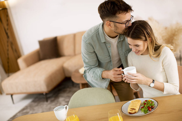 Kaunis nuori pari puhuu ja hymyilee syödessään terveellistä kotona. - Valokuva, kuva