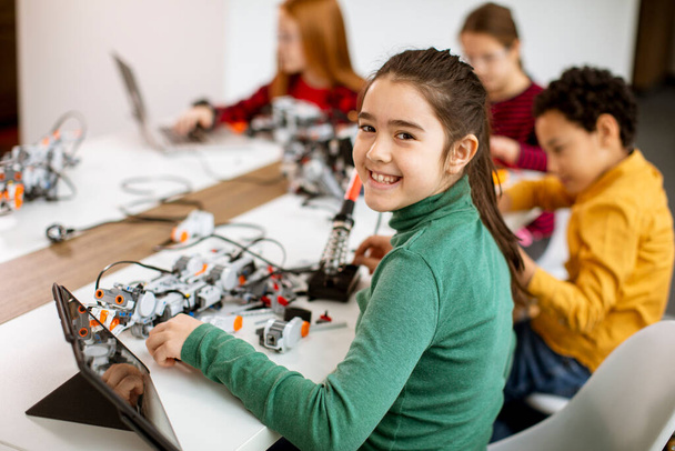 Robot sınıfında elektrikli oyuncak ve robot programlayan bir grup mutlu çocuk. - Fotoğraf, Görsel