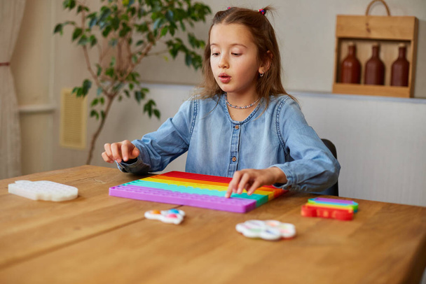 Kleines Mädchen spielt mit großem Silikonpopit, einfachem Grübchen, Bubble-Fidget-Spielzeug, Antistress-Sensor-Spielzeug zu Hause. Das Konzept der psychischen Gesundheit popit Spielzeug - Foto, Bild