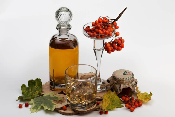 Composition with a bottle and a glass of strong mountain ash tincture and ripe rowan berries on a light background. - Fotoğraf, Görsel