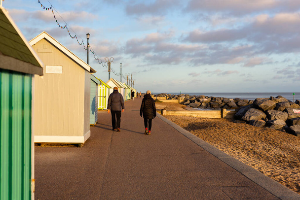 Strandhutten in Felixstowe, Suffolk, Engeland met een onbekend bejaardenpaar dat wegloopt van de camera - Foto, afbeelding