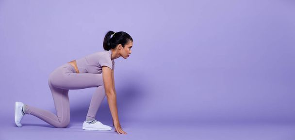 Full length Asian slim Fitness woman exercise warm up stretch spring jumps legs, studio lighting purple background copy space, concept Woman Can Do athlete in Very Peri color block mood tone - Photo, image