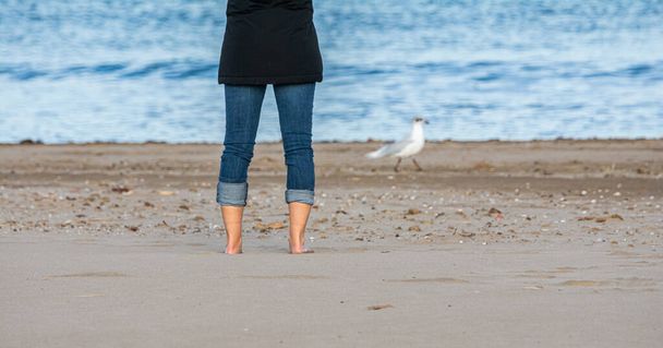 Uma mulher está na areia de frente para o mar e vê o verão. - Foto, Imagem