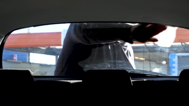 Mężczyzna czyści tylną szybę samochodu tkaniną - Materiał filmowy, wideo