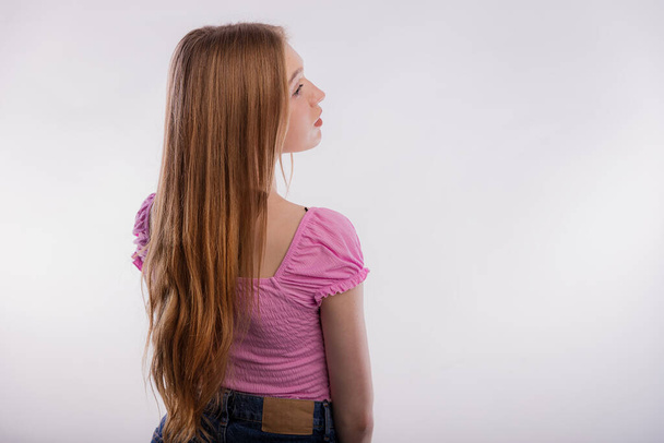 Visão traseira de uma jovem loira com cabelo comprido. Feminino olhando para o lado isolado no espaço de cópia de fundo branco. Cabelo bonito e saudável, cuidado e coloração. - Foto, Imagem