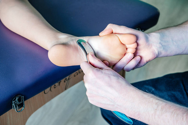 Fisioterapeuta que fija el dolor del talón plantar con la herramienta IASTM guasha - Foto, imagen