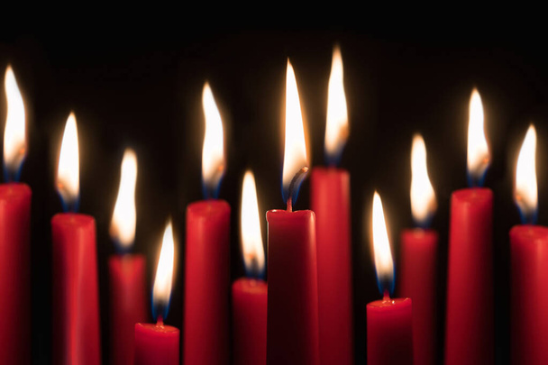 Δώδεκα κόκκινα κεριά που καίγονται μπροστά από το μαύρο φόντο του στούντιο - Φωτογραφία, εικόνα