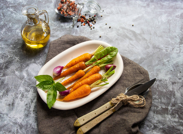 gebakken geroosterde baby wortelen in een bord, basilicum en kruiden veganistisch gerecht. Bovenaanzicht - Foto, afbeelding