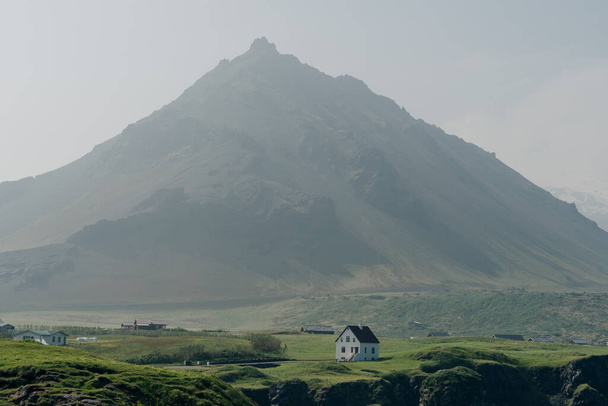 Pole s vesnicí na úpatí sopečného vrcholu Gatklettur. . Kvalitní fotografie - Fotografie, Obrázek