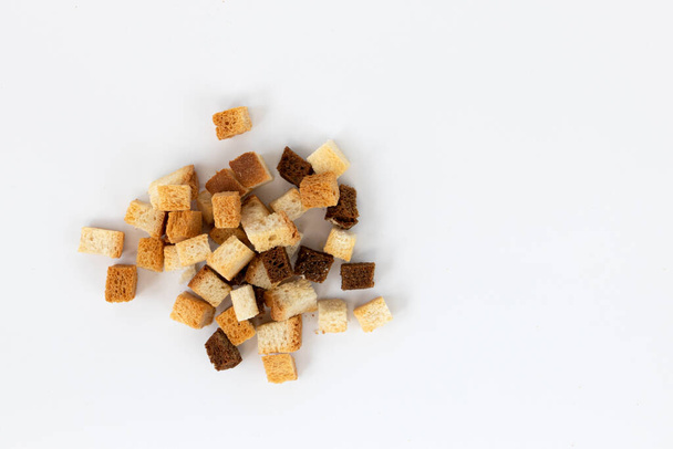 pile of homemade bread croutons isolated on white background, top view, crispy bread cubes, dry rye and wheat crumbs, crouoton or roasted crackers cube heap - Photo, image