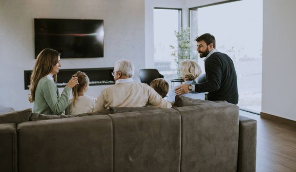 Famille multi-génération assis ensemble sur le canapé à l'appartement moderne et regarder la télévision - Photo, image