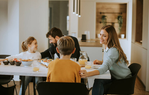 Young happy family talking while having breakfast at dining table at apartment - Fotoğraf, Görsel