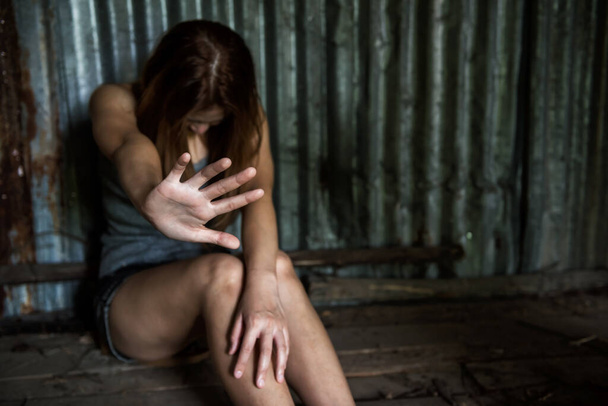 Mujer asiática joven sentarse y mostrar señal de mano parada para prevenir la violencia y la violación en el piso de la cabina de abandono. Acoso sexual o concepto de víctima de rehenes. - Foto, Imagen