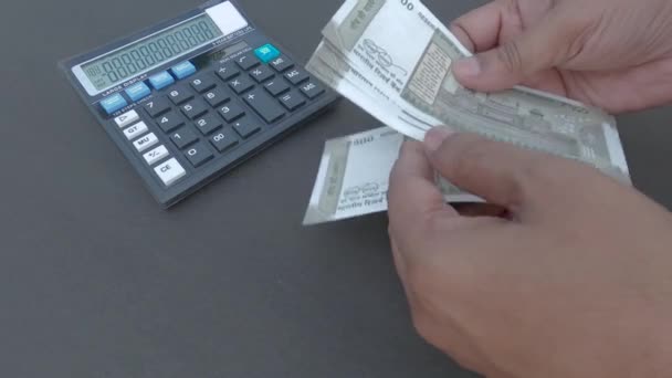 Human hand counting new 500 rupee indian currency note against a calculator and a pen placed on table. High angle view. Close up. Banking Business Finance Background. - Footage, Video