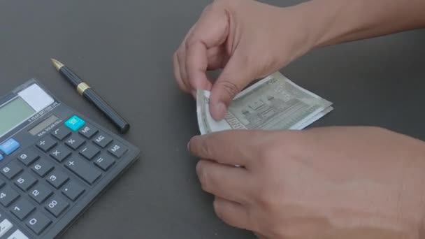 Ihmisen käsi laskee uutta 500 rupian Intian valuutan seteliä laskimeen ja kynään, joka on asetettu pöydälle. Korkeassa kulmassa. Sulje se. Pankkien rahoituksen taustaa. - Materiaali, video
