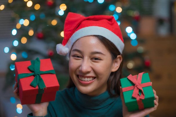 Happy smiling young Asian woman in santa claus hat holding many gift box celebrate Christmas and new year - Fotografie, Obrázek