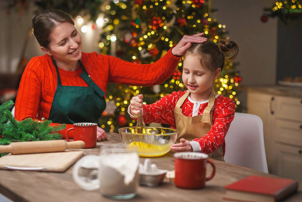 Merry Christmas. My daughter helps my mother cook. Family cooking of festive food. Mother and daughter are making Christmas cookies. happy holidays. Evening time, happy family in the kitchen. - Foto, Bild