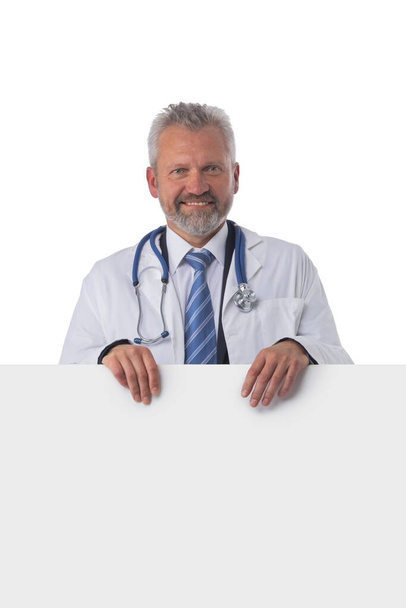 Mature male doctor holding blank placard banner isolated on white background - Foto, Imagen