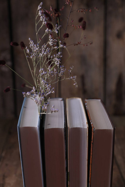 Dried flowers between books on an old wooden background - Foto, imagen