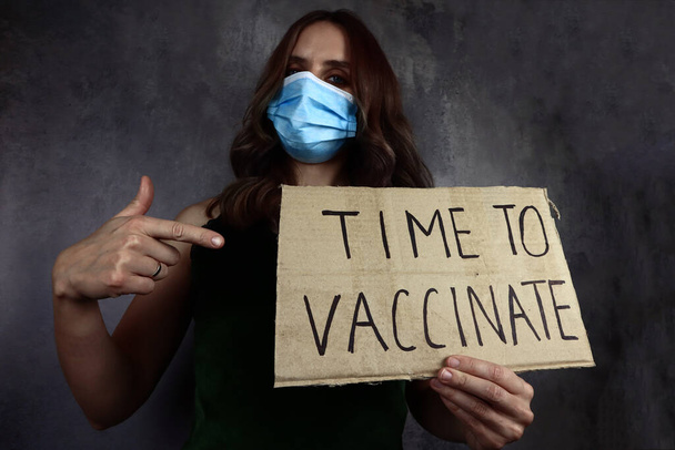 молода жінка в медичній масці з часом вакцинувати плакат
 - Фото, зображення