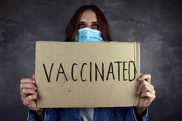 молода жінка в медичній захисній масці з плакатом для вакцин
 - Фото, зображення