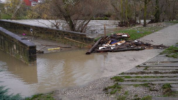 Мост был затоплен водой и заброшен бревнами, которые несли течение. наводнение в городе Памплона - Фото, изображение