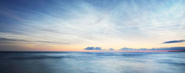 夏の冬至の夜にバルト海の海岸の上に夜行性の雲を持つ星空。黄金の流れる太陽。長時間露光。幻想的な雲景。自然パターンだ。抽象美術。ラトビア - 写真・画像