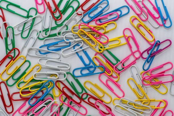 Lot of paper clips in various vibrant colors spread out on a white background - Zdjęcie, obraz