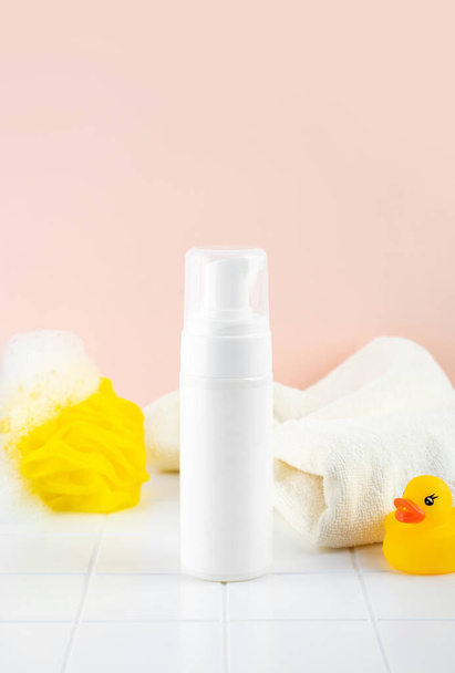 Natural Hypoallergenic Foam for bathing children. White Plastic pump bottle. children's cosmetics. Bottles, towel and duck toy and a washcloth. - Photo, Image