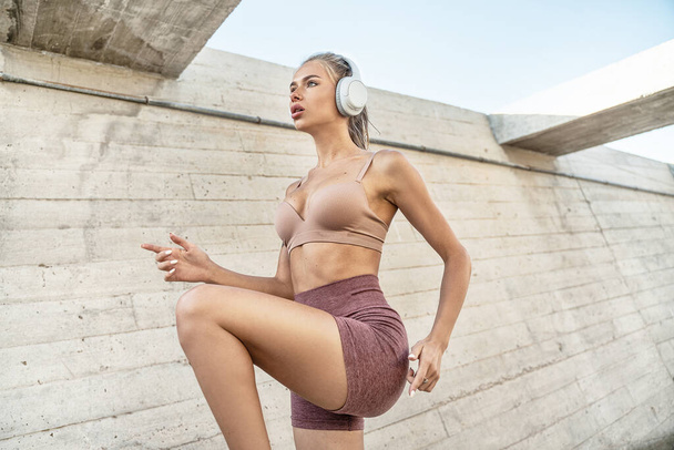 Young beautiful fit caucasian woman exercising outdoors. Attractive girl with headphones running. Healthy sporty lifestyle concept. Morning routine.  - Fotoğraf, Görsel