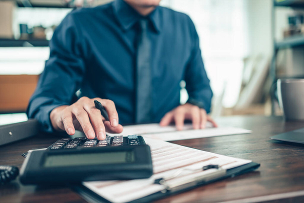 Financial businessman working on desk office using a calculator to calculate calculating corporate income tax data And analyzing charts of financial.  finance and accounting concept. - Photo, image