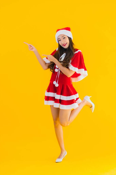 Portrait beautiful young asian woman christmas clothes and hat smile happy with other action on yellow isolated background - Photo, image