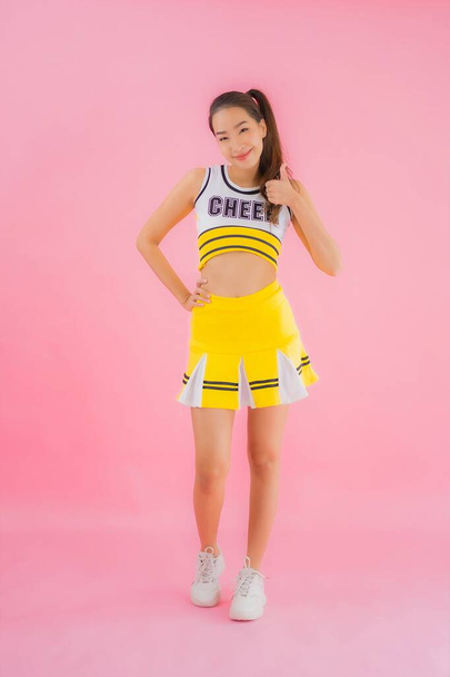 Portrait beautiful young asian woman cheerleader on pink isolated background - Photo, Image