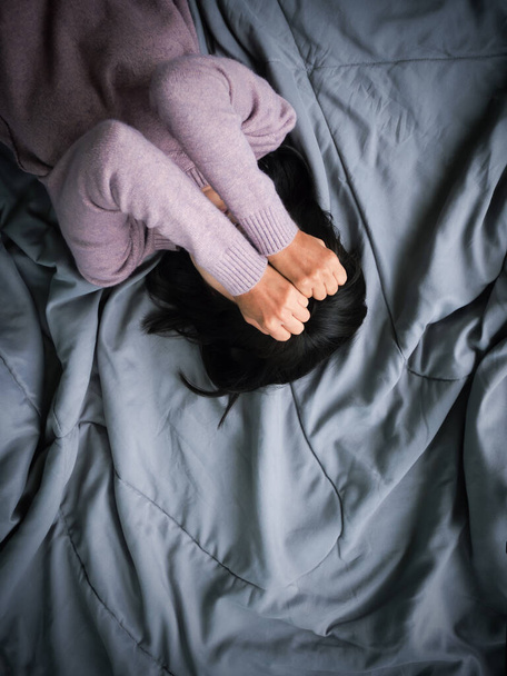 Yalnız bir kadın el örtüsü ile uyur ve yatakta ağlar. Boş alanı olan üst görünüm. Kırık kalp, sorun, üzgün, hayal kırıklığına uğramış konsept. - Fotoğraf, Görsel