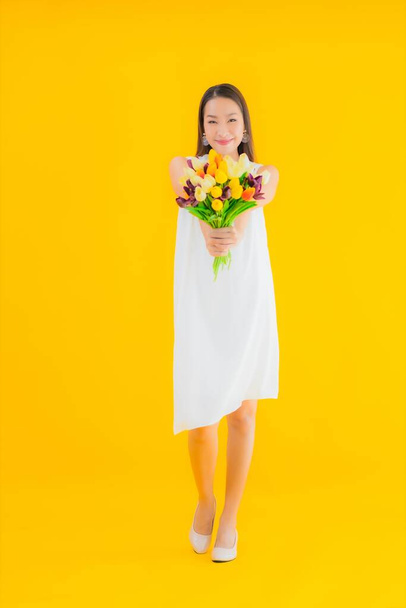Porträt schöne junge asiatische Frau mit Blume auf gelbem Hintergrund - Foto, Bild
