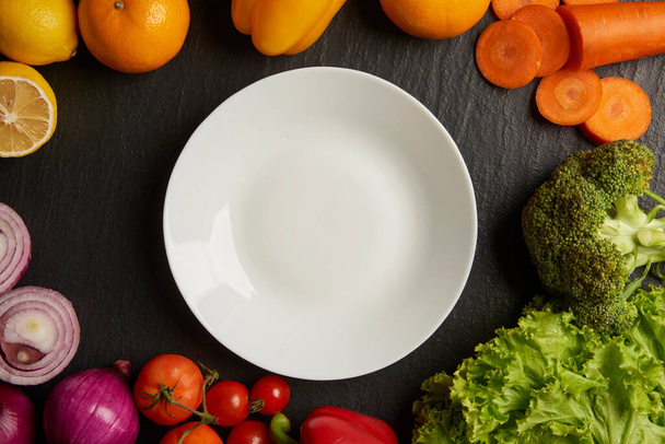 concept de légumes différents types de légumes étant placés autour d'une plaque blanche sur le fond noir. - Photo, image