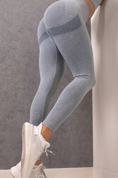 legs of young woman in grey sportswear posing in studio - Fotó, kép