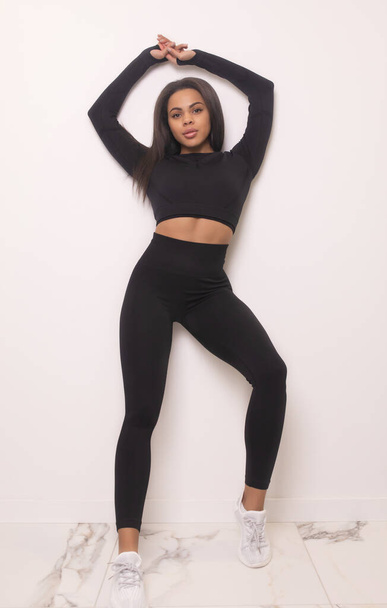 full length view of fit african american woman in black sportswear posing in studio - Foto, Bild